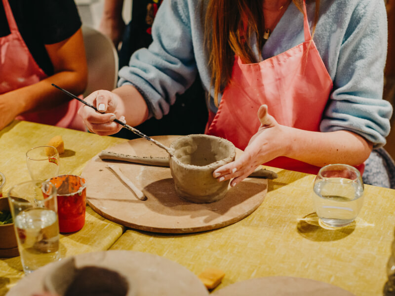 A woman brushing clay at a pottery making workshop.